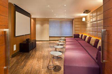 Media room with full wall of continuous lounge chair with individual tables