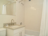 White-on-white ceramic tile bathroom with marble vanity and under-sink storage